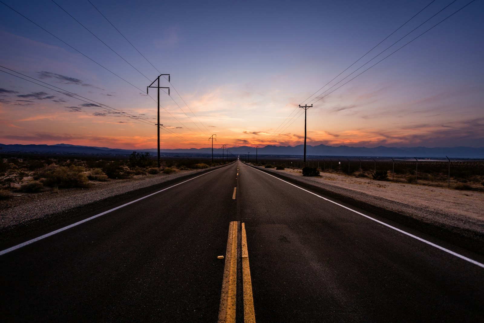 An open road stretching toward the horizon at sunset